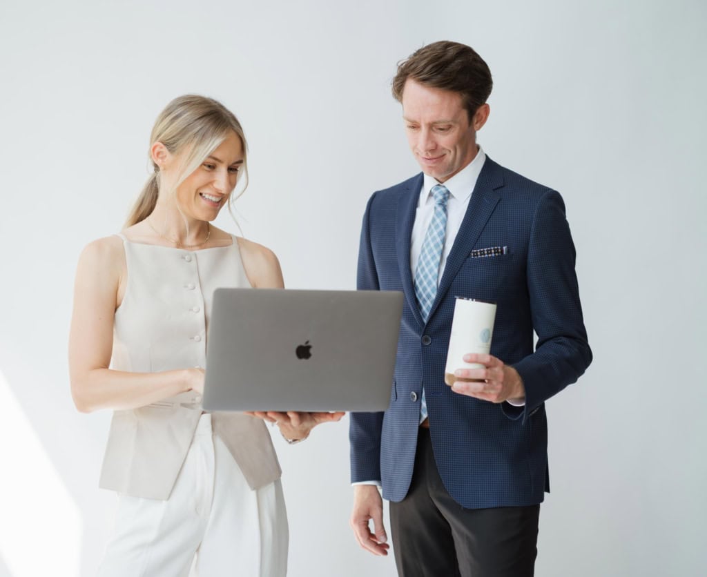 Two real estate advisors with the North Pacific Homes Group, eXp Realty, in Victoria, BC, look at a laptop together.