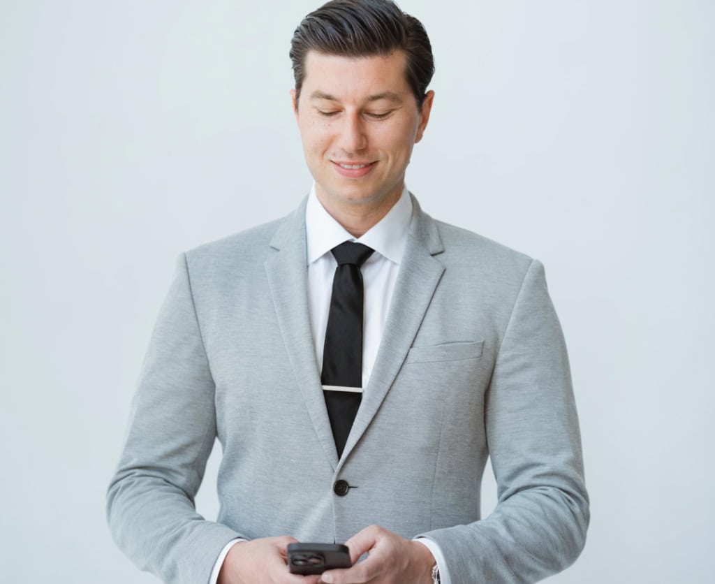 Professional real estate expert in a grey suit checking phone — North Pacific Homes Group with eXp Realty, Victoria BC real estate insights 2025