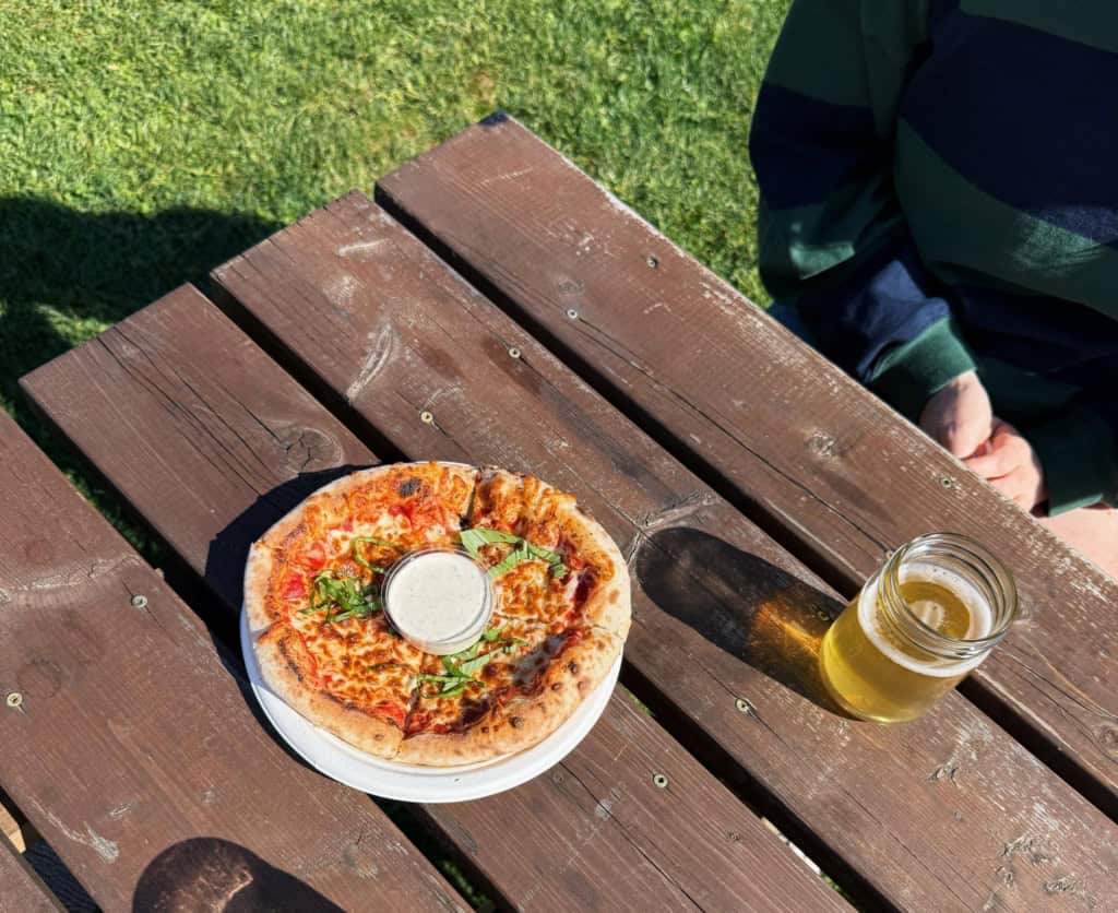Picnic table at the Junction Orchard & Cidery Market with pizza and cider.