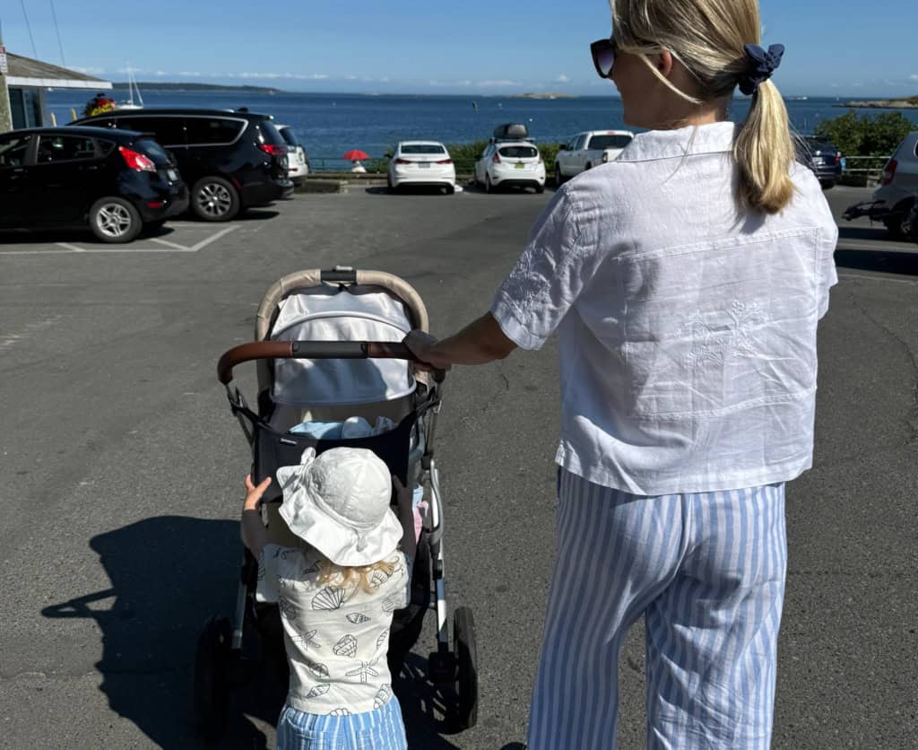 Mom and daughter push stroller towards the beach in Victoria, BC.