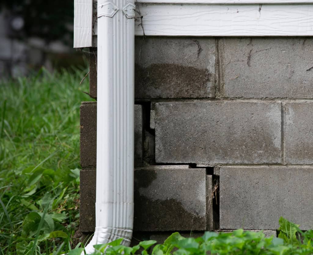 Close up of the foundation and downspout of a home.